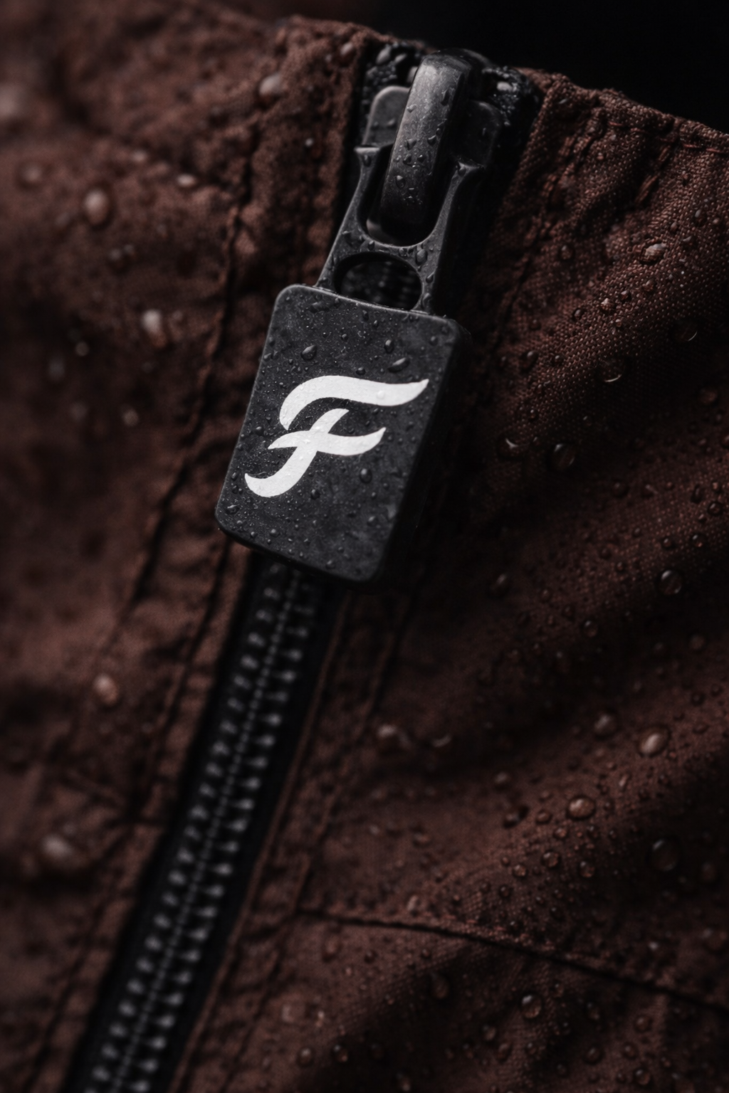 Close-up of the FLEUVE branded zipper pull with water droplets