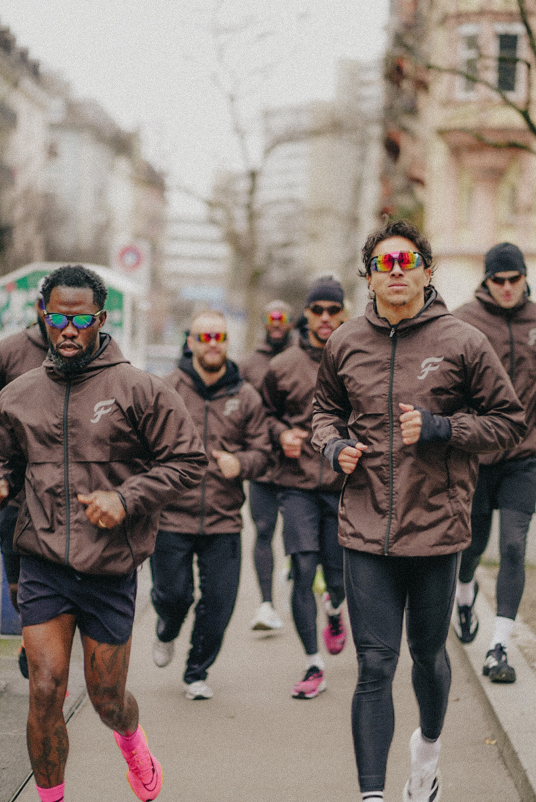 Runners moving through the city in the FLEUVE performance rain jacket